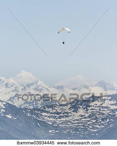 Stock Photography - "Paraglider against a blue sky, snow-capped peaks of the Alps at the back". Fotosearch