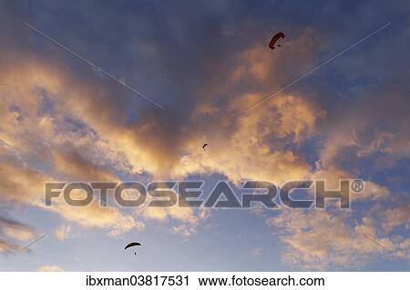Stock Image - "Paraglider in front of clouds at dusk, Puerto Naos, La Palma, Canary Islands, Spain, Europe". Fotosearch
