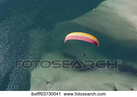 "Paraglider over the Maggia river delta with naturally formed water and rocks terrain, Locarno, Kanton Tessin, Switzerland, Europe" View Large Photo Image Stock Image - "Paraglider over the Maggia river delta with naturally formed water and rocks terrain, Locarno, Kanton Tessin, Switzerland, Europe". Fotosearch