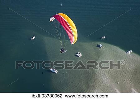 "Paraglider over the Maggia river delta with naturally formed water and rocks terrain, natural beach, Locarno, Kanton Tessin, Switzerland, Europe" View Large Photo Image Stock Image - "Paraglider over the Maggia river delta with naturally formed water and rocks terrain, natural beach, Locarno, Kanton Tessin, Switzerland, Europe". Fotosearch