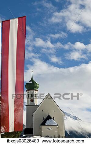 Stock Photo - "Parish and pilgrimage church of St. Bartholomew, Baroque church, with an Austrian flag, Bartholomaberg, Montafon, Vorarlberg, Austria, Europe". Fotosearch
