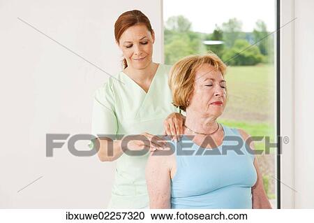 Stock Image - Patient being treated on her shoulder by a physiotherapist. Fotosearch