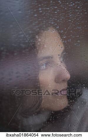 Pensive woman behind a window with rain drops View Large Photo Image Picture - Pensive woman behind a window with rain drops. Fotosearch