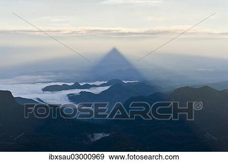 Stock Photo - "Pilgrim mountain, sun creating a triangle shadow in the landscape, image of God, Buddhist temple, Adam's Peak, Sri Pada, Dalhousie, Zentrales Hochland, Sri Lanka, Asia". Fotosearch
