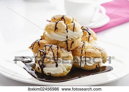 Stock Photograph - "Plate of cream puffs, choux pastry filled with cream and covered with warm chocolate". Fotosearch