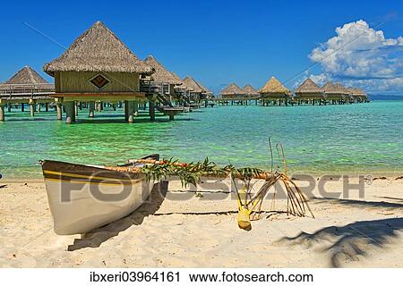 Stock Image - "Polynesian outrigger canoe in front of pile bungalow complex, South Pacific, Bora Bora, French Polynesia, Oceania". Fotosearch