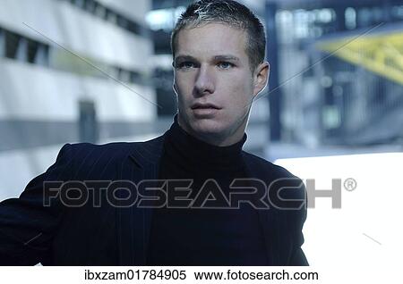 Stock Photography - "Portrait of a businessman wearing a dark suit, bank building at the back". Fotosearch