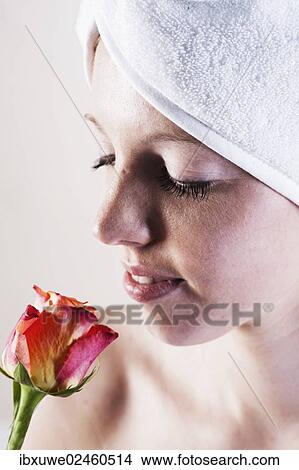 Portrait of a smiling young woman smelling a rose with a towel wrapped around her head View Large Photo Image Picture - Portrait of a smiling young woman smelling a rose with a towel wrapped around her head. Fotosearch