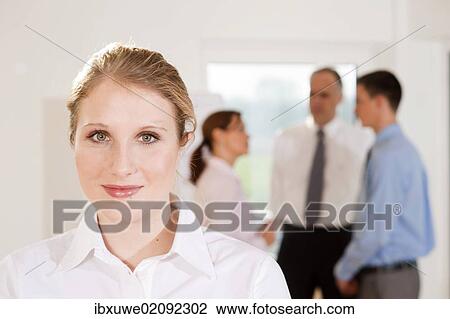 "Portrait of a young woman in an office, with her colleagues behind her" View Large Photo Image Stock Image - "Portrait of a young woman in an office, with her colleagues behind her". Fotosearch