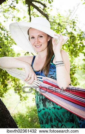 Stock Image - Pregnant woman at hammock in the garden. Fotosearch