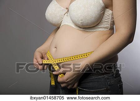 Stock Photography - "Pregnant woman measuring her abdominal girth, 13th week". Fotosearch