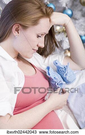 Pregnant woman with baby shoes sitting in front of a Christmas tree View Large Photo Image Stock Image - Pregnant woman with baby shoes sitting in front of a Christmas tree. Fotosearch