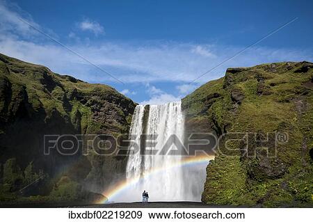 "Rainbow, couple watching the Skogafoss waterfall on the Skoga river, ring road, Suourland, Sudurland, southern Iceland, Iceland, Europe" View Large Photo Image Stock Photo - "Rainbow, couple watching the Skogafoss waterfall on the Skoga river, ring road, Suourland, Sudurland, southern Iceland, Iceland, Europe". Fotosearch