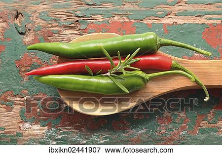 Stock Photo - Red and green peppers with a wooden spoon on an old wooden board. Fotosearch