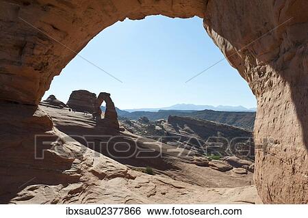 Stock Photograph - "Red sandstone, Delicate Arch, a natural stone arch seen through the window of Frame Arch, Arches National Park, Utah, Western United States, United States of America, North America". Fotosearch