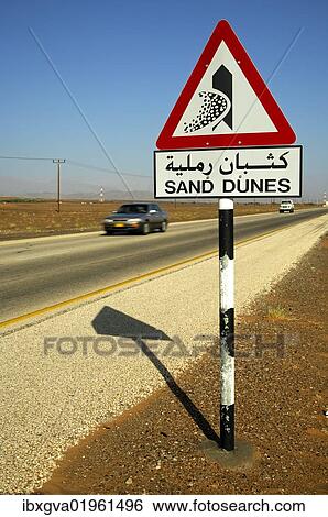 "Road sign in English and Arabic warning of shifting sand dunes at a desert road, Sultanate of Oman, Middle East, Asia" View Large Photo Image Stock Photograph - "Road sign in English and Arabic warning of shifting sand dunes at a desert road, Sultanate of Oman, Middle East, Asia". Fotosearch