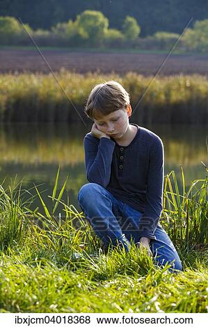 "Sad boy sitting on a small lake, Wandersleben, Thuringia, Germany, Europe" View Large Photo Image Stock Photo - "Sad boy sitting on a small lake, Wandersleben, Thuringia, Germany, Europe". Fotosearch