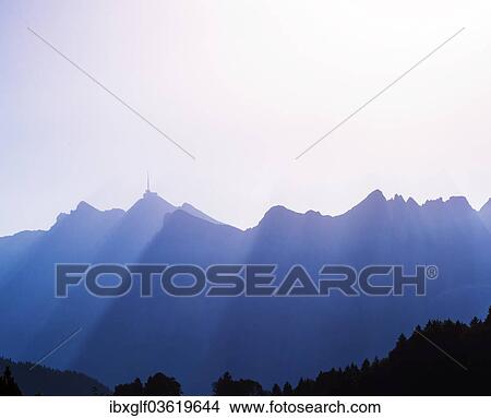 "Saentis mountain range, silhouetted with sun rays, Nesslau-Krummenau, Canton of St. Gallen, Switzerland, Europe" View Large Photo Image Picture - "Saentis mountain range, silhouetted with sun rays, Nesslau-Krummenau, Canton of St. Gallen, Switzerland, Europe". Fotosearch