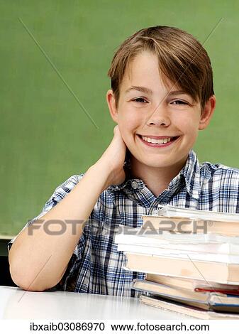 "Schoolboy in front of a school blackboard with a stack of books, smiling" View Large Photo Image Stock Image - "Schoolboy in front of a school blackboard with a stack of books, smiling". Fotosearch