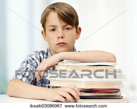 Stock Photo - "Schoolboy with a stack of books, looking serious". Fotosearch