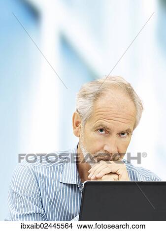 "Senior, behind a laptop with a thoughtful expression" View Large Photo Image Picture - "Senior, behind a laptop with a thoughtful expression". Fotosearch