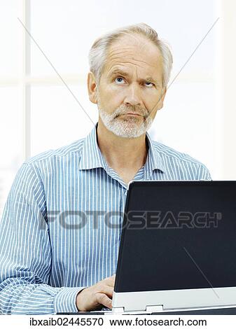 Stock Image - "Senior, behind a laptop with a stressed expression". Fotosearch