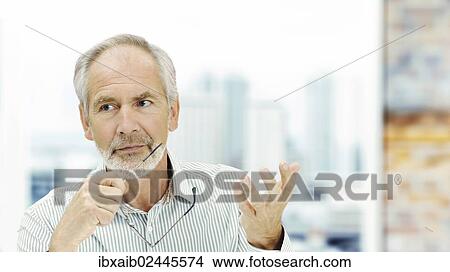"Senior, with a serious expression and holding a pair of glasses, gesticulating" View Large Photo Image Picture - "Senior, with a serious expression and holding a pair of glasses, gesticulating". Fotosearch