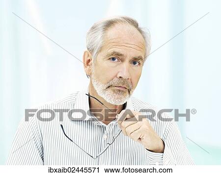 "Senior, with a serious expression and holding a pair of glasses" View Large Photo Image Stock Image - "Senior, with a serious expression and holding a pair of glasses". Fotosearch