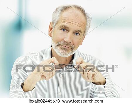 Stock Image - "Senior, with a serious expression and holding a pair of glasses". Fotosearch