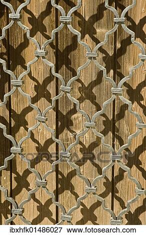Stock Photo - Shadow of a grid on a wooden door. Fotosearch