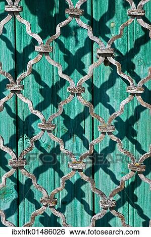 Stock Photograph - Shadow of a grid on a wooden door. Fotosearch