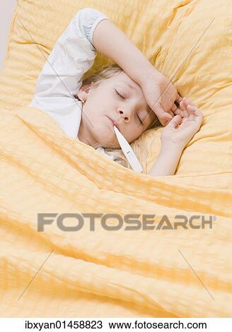 Stock Image - Sick girl with clinical thermometer in bed. Fotosearch