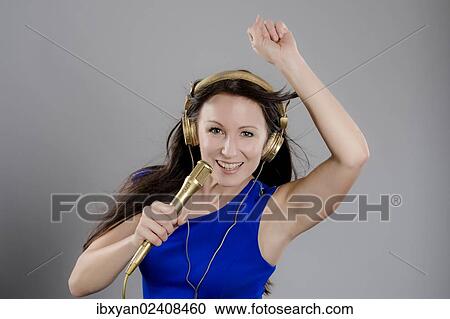"Singer, woman wearing golden headphones and holding a microphone" View Large Photo Image Stock Image - "Singer, woman wearing golden headphones and holding a microphone". Fotosearch