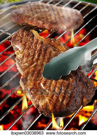Stock Image - Sirloin steak on a BBQ grill. Fotosearch