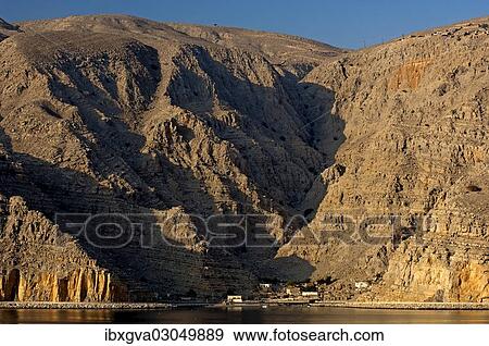 "Small village in the morning light at the foot of the rocky cliffs of a fjord in the Musandam Peninsula on the Persian Gulf, Musandam Governorate, Oman, Asia" View Large Photo Image Stock Photo - "Small village in the morning light at the foot of the rocky cliffs of a fjord in the Musandam Peninsula on the Persian Gulf, Musandam Governorate, Oman, Asia". Fotosearch