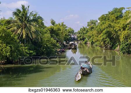 "Small wooden motorboat passing through a water channel surrounded by tropical vegetation, Hue, Vietnam, Asia" View Large Photo Image Stock Image - "Small wooden motorboat passing through a water channel surrounded by tropical vegetation, Hue, Vietnam, Asia". Fotosearch