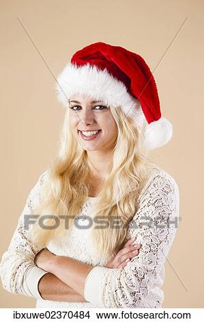 Picture - Smiling blond woman wearing a Santa hat. Fotosearch