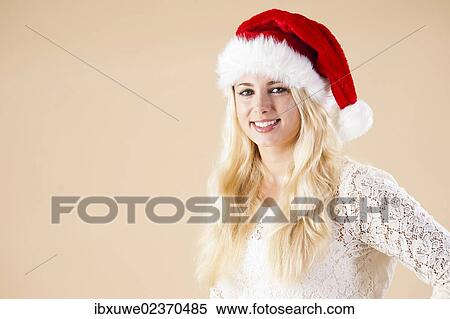Stock Photography - Smiling blond woman wearing a Santa hat. Fotosearch