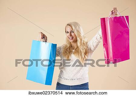 Smiling blond young woman with shopping bags while shopping View Large Photo Image Picture - Smiling blond young woman with shopping bags while shopping. Fotosearch