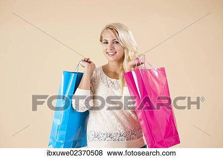 Smiling blond young woman with shopping bags while shopping View Large Photo Image Stock Photo - Smiling blond young woman with shopping bags while shopping. Fotosearch