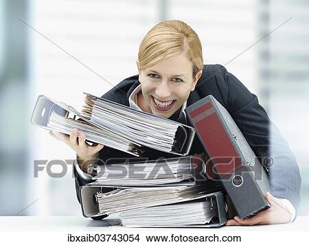 Smiling business woman holding a stack of folders View Large Photo Image Picture - Smiling business woman holding a stack of folders. Fotosearch