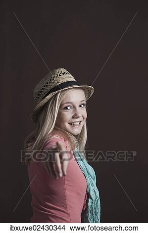 Smiling teenage girl wearing a hat pointing towards the camera View Large Photo Image Picture - Smiling teenage girl wearing a hat pointing towards the camera. Fotosearch