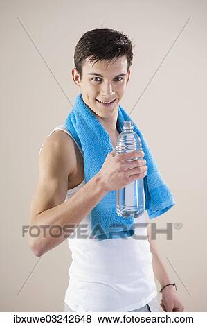 "Smiling young man after doing sport holding a water bottle in his hand, Mannheim, Baden-Wurttemberg, Germany, Europe" View Large Photo Image Stock Photo - "Smiling young man after doing sport holding a water bottle in his hand, Mannheim, Baden-Wurttemberg, Germany, Europe". Fotosearch