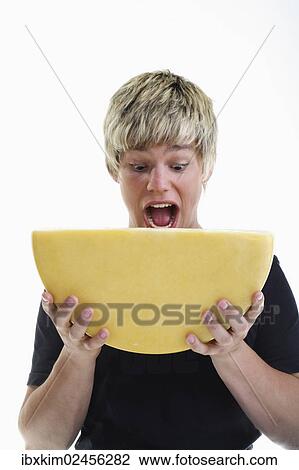 Stock Image - Smiling young man holding half a wheel of cheese. Fotosearch