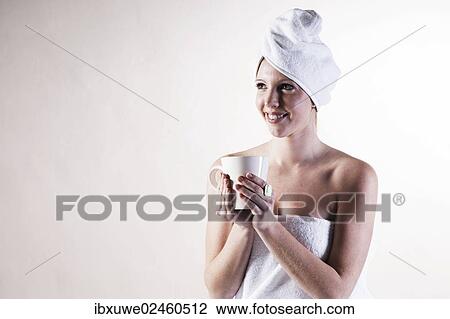Smiling young woman with a towel wrapped around her head holding a teacup View Large Photo Image Stock Image - Smiling young woman with a towel wrapped around her head holding a teacup. Fotosearch