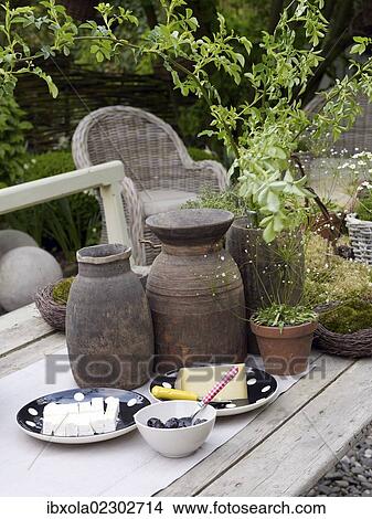 "Still life, cheese and olives, surrounded by decorative garden accessories on an old wooden table in a romantic garden" View Large Photo Image Picture - "Still life, cheese and olives, surrounded by decorative garden accessories on an old wooden table in a romantic garden". Fotosearch