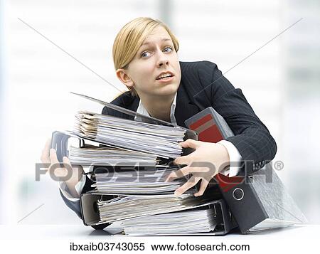 Stressed business woman holding a stack of folders View Large Photo Image Stock Photography - Stressed business woman holding a stack of folders. Fotosearch