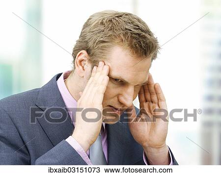 Stock Image - Stressed businessman holding his hands against his temples. Fotosearch