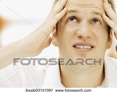 Stock Photo - Stressed businessman holding his hands against his temples. Fotosearch