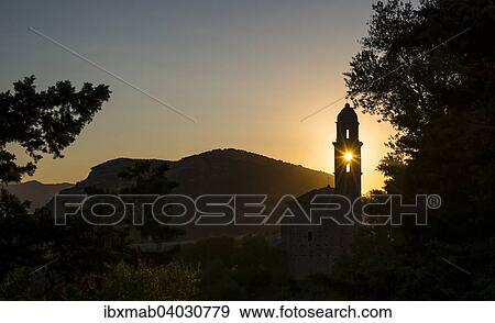 Stock Photo - "Sun shining through a belfry, silhouette of a church tower, evening mood, sunset, Haute-Corse, Corsica, France, Europe". Fotosearch